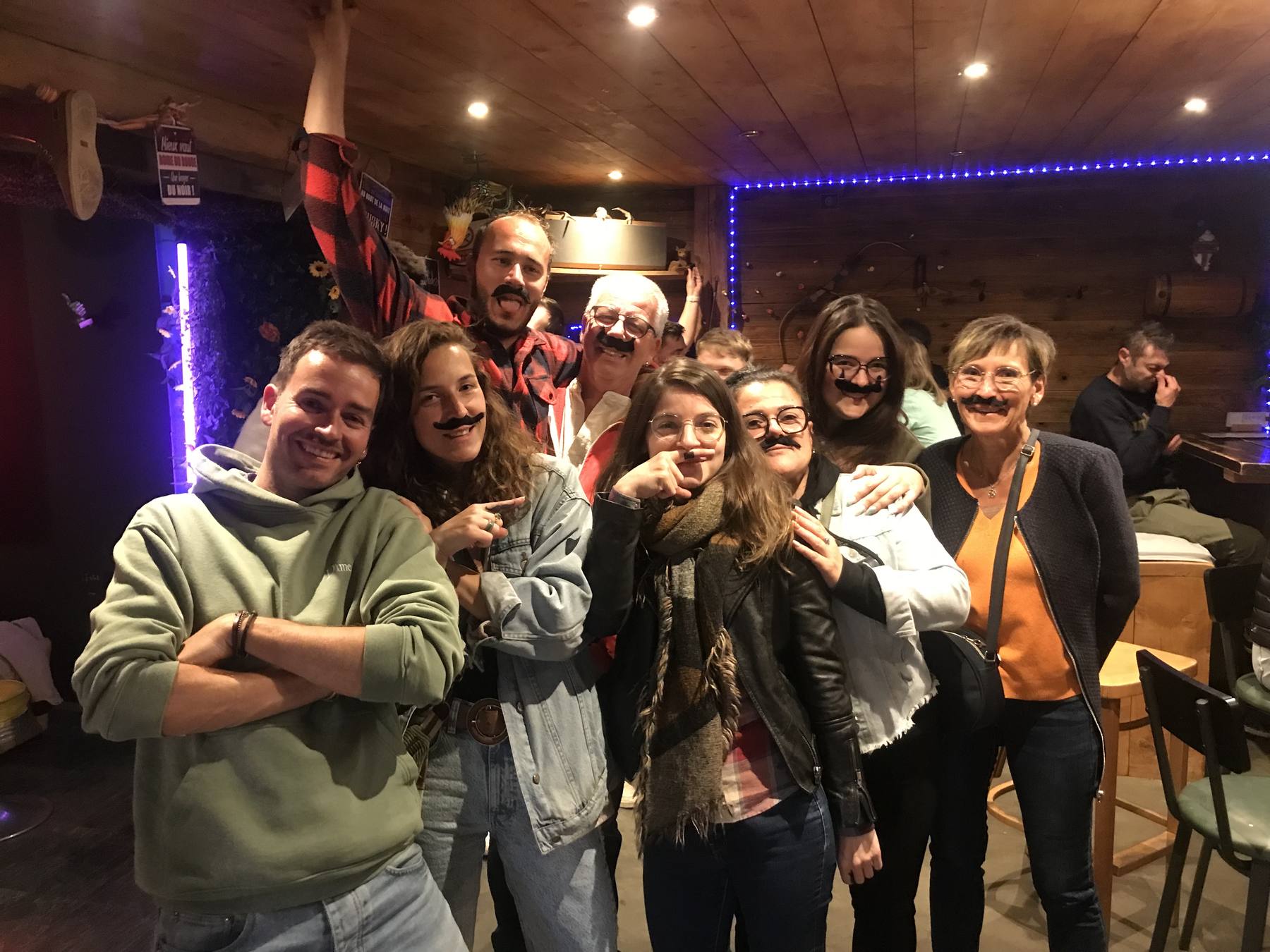 Une bande d'habitués du PIC, fausses moustaches sur le visage, dans la salle boisée éclairée au néon